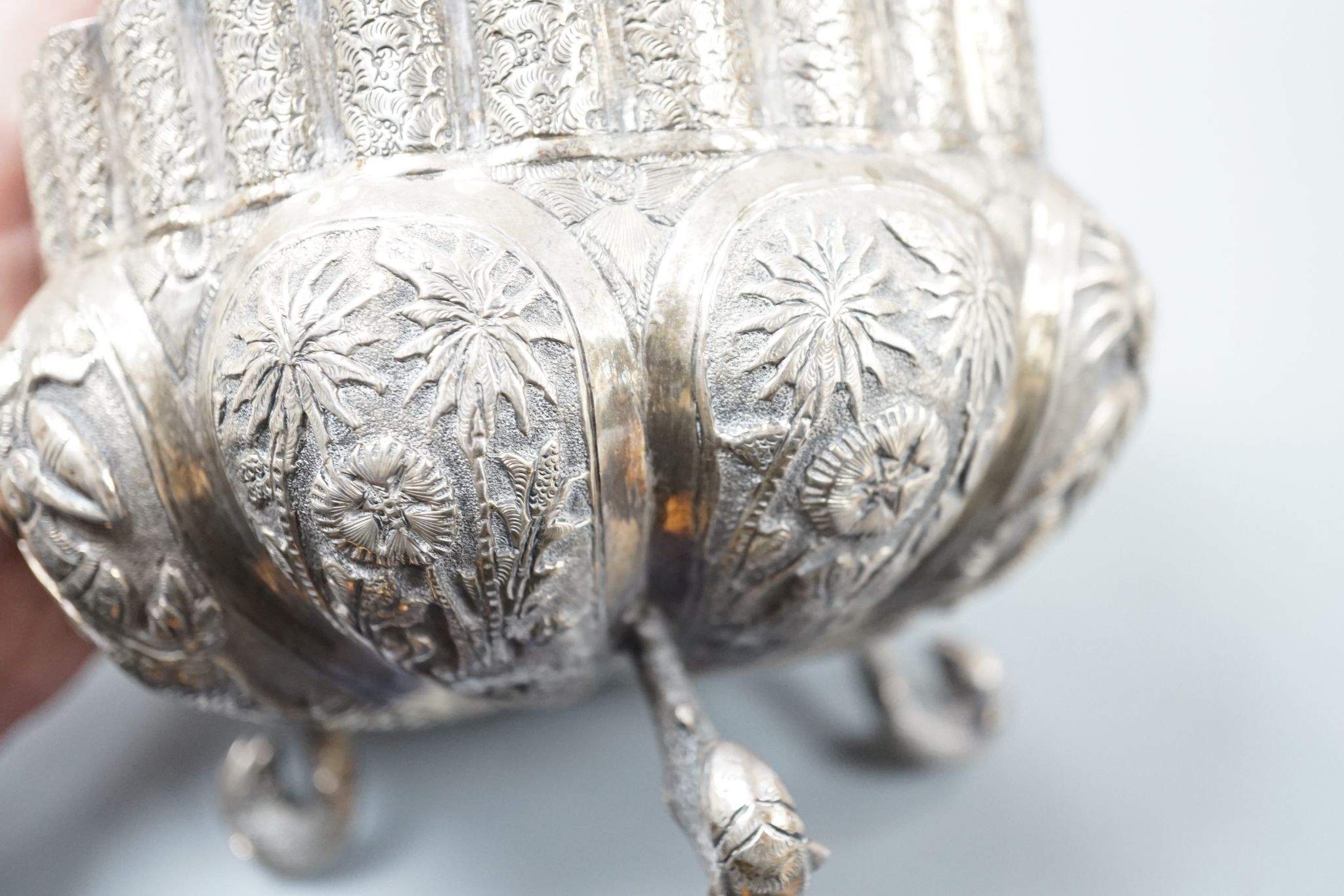 An Indian embossed white metal bowl, on three dolphin feet, diameter 13cm, 10oz.